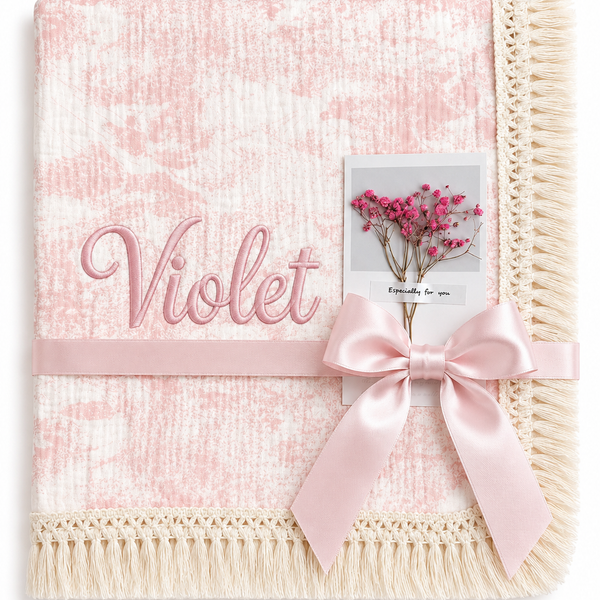 Blush Naturel pink patterned muslin blanket with Violet embroidered in pink, cream fringed edging and pale pink ribbon.