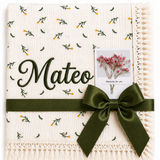 Cream Dandelions muslin blanket with delicate green and yellow botanical print, Mateo name embroidery and dark-green ribbon.