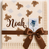 Cream teddy-print muslin baby blanket personalised with Noah embroidered in brown, with a fringed border.